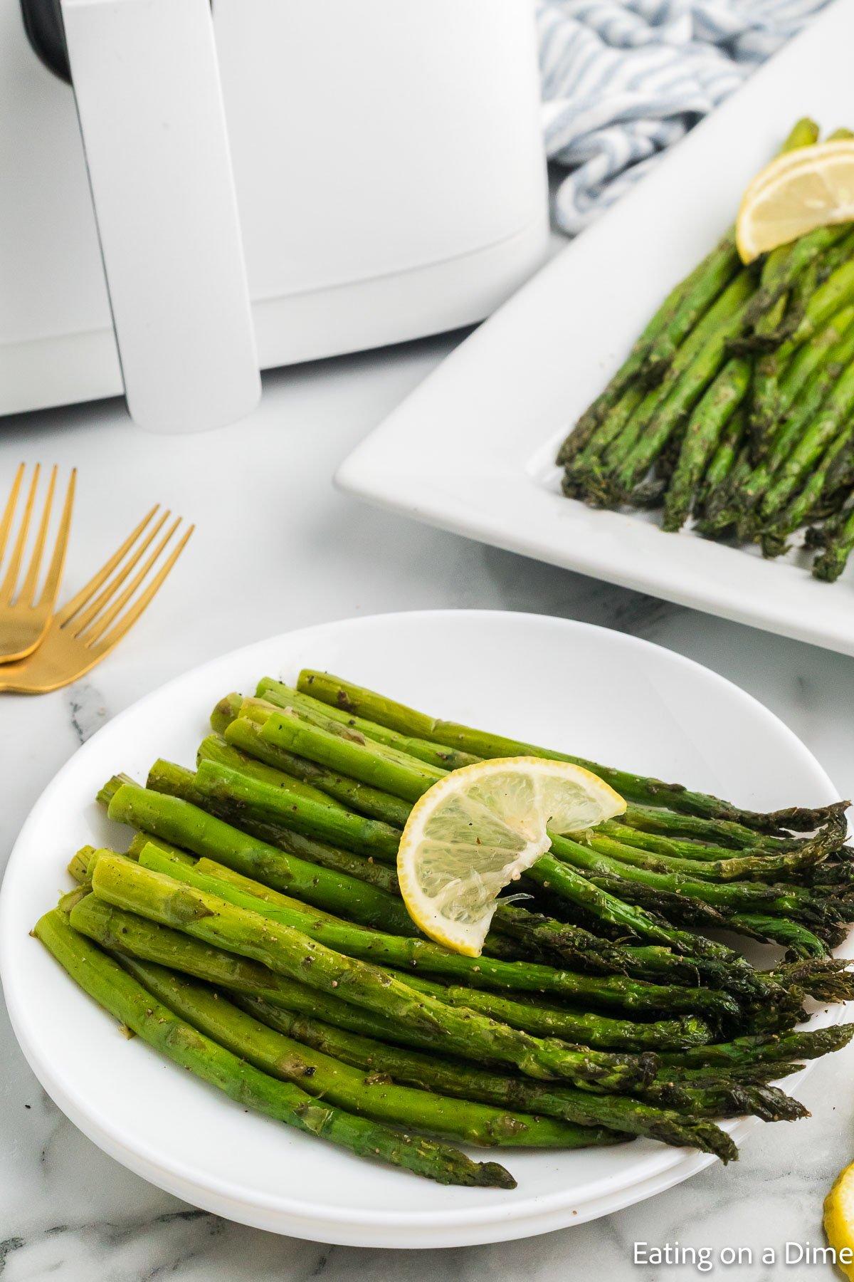 Cooked Asparagus on a plate topped with slice lemons on a white plate