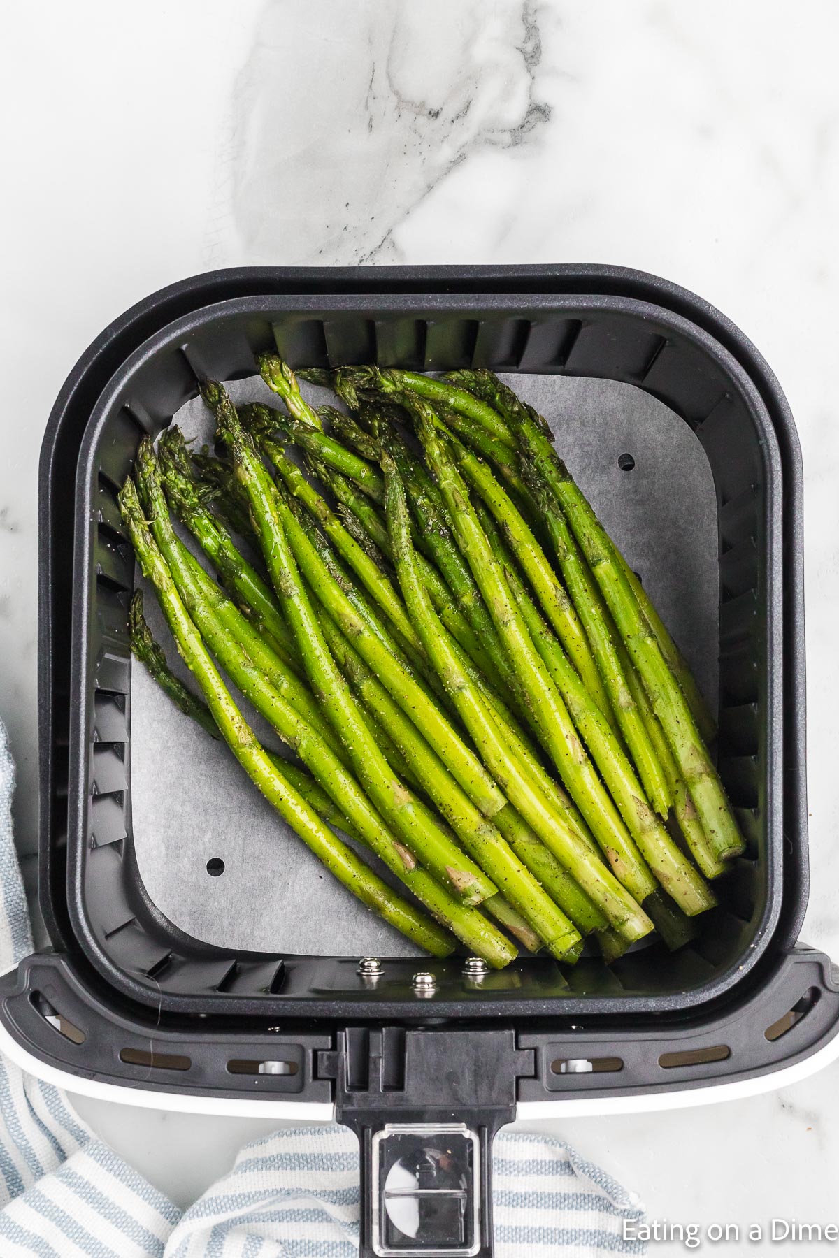 Placing the asparagus in a air fryer basket