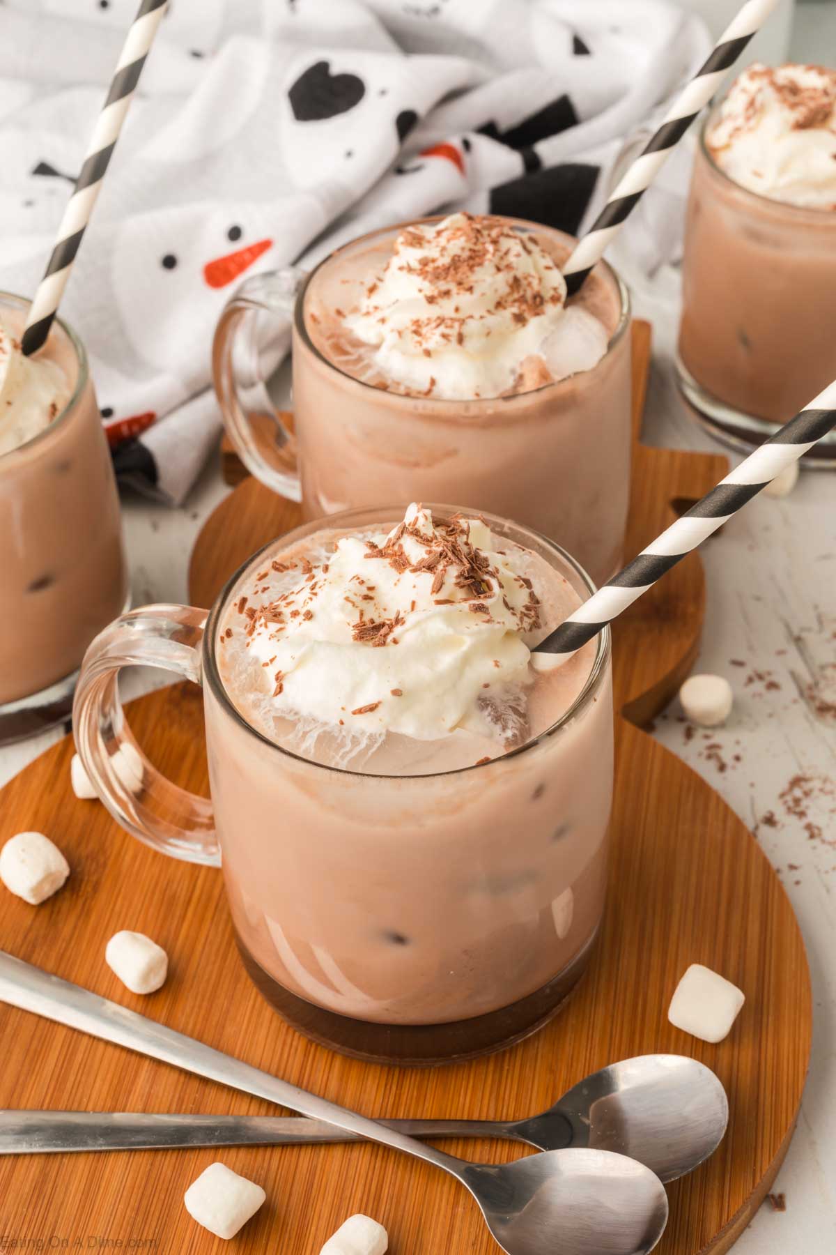 Ice Hot Chocolate in a clear mug topped with whipped cream and shaved chocolate with a straw