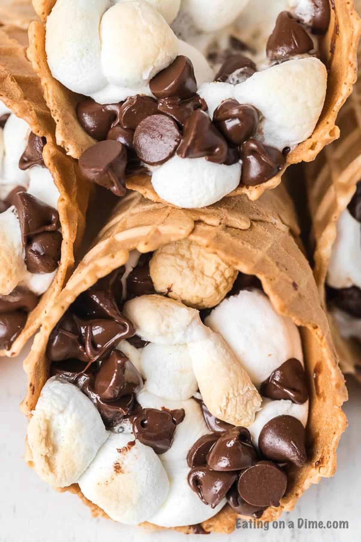 Check out how to make s’mores campfire cones that are fun and less messy than traditional s’mores. Camp fire cones are a blast and fun to make. Campfire sugar cone s’mores are a fun and easy dessert for any camping treat. Campfire s’mores cones will be your favorite summer treat! #eatingonadime #smoresrecipes #campfirecones #easydesserts 