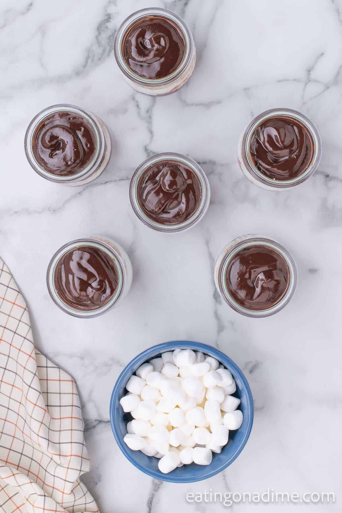 Jars of pudding with a bowl of marshmallows