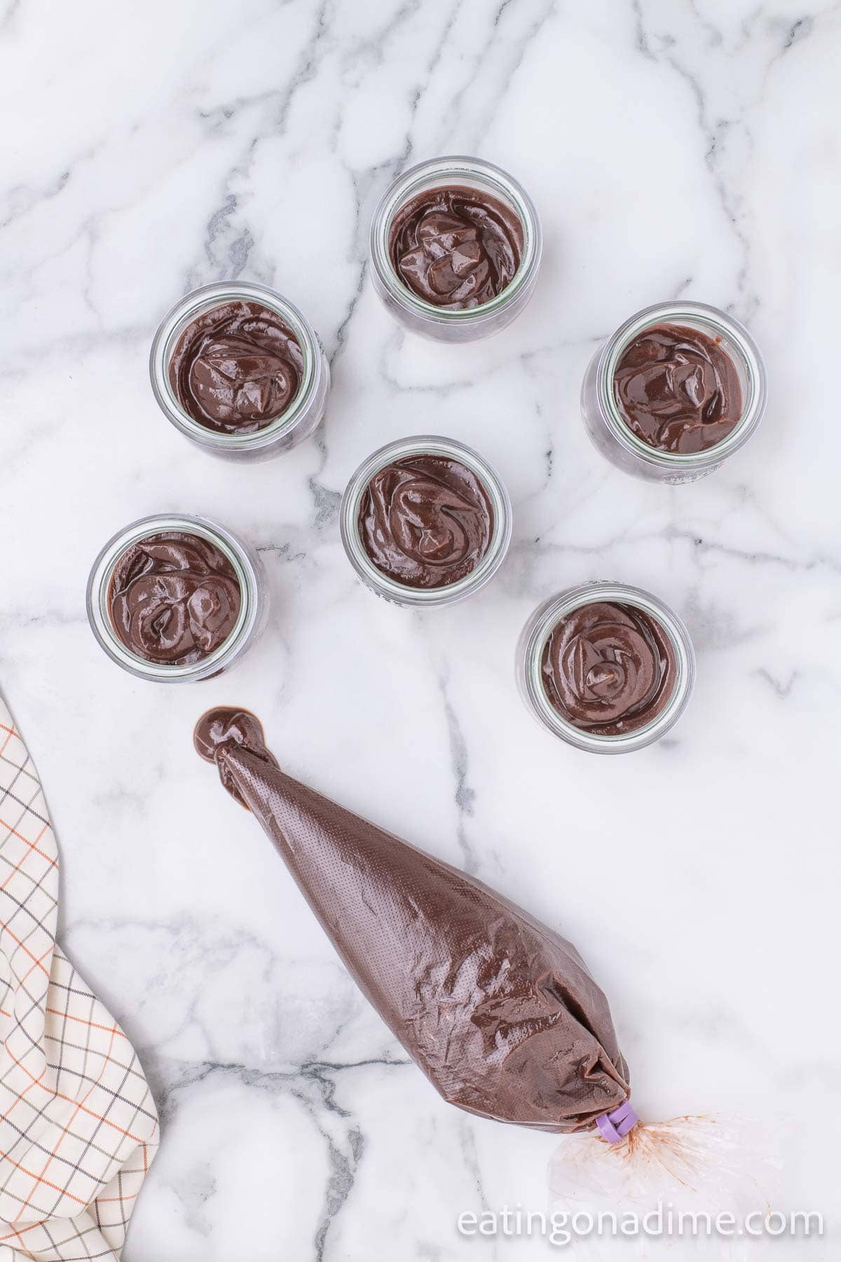 Piping chocolate into jars on the graham cracker crust