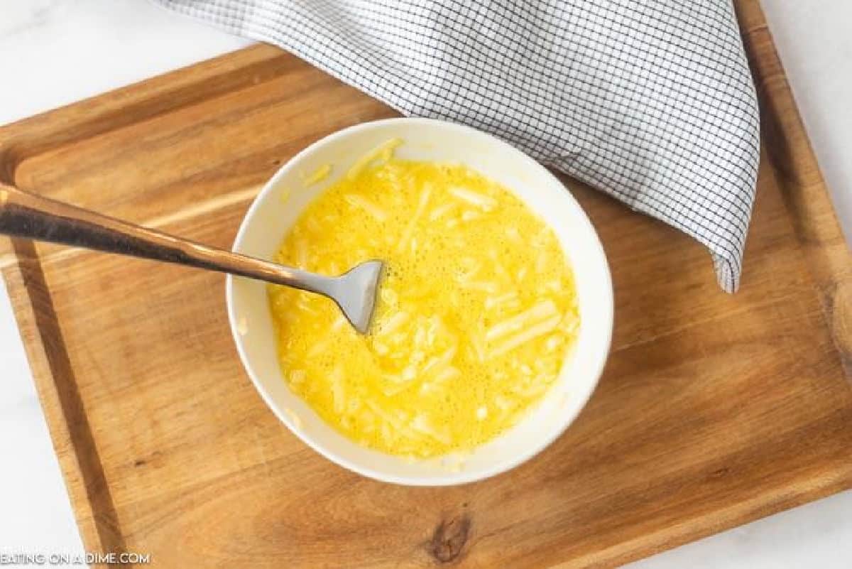 Scrambled egg and cheese mixed together in a bowl with a fork.