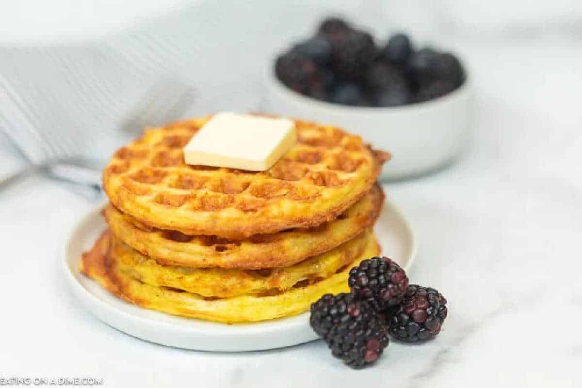 Learn how to make a chaffle that is great if you are following a Keto or low carb diet. This chaffle recipe is easy to make with just 3 ingredients. This simple chaffle recipe keto easy can be made in minutes with just a few ingredients. You are going to love this easy chaffle recipe. #eatingonadime #chafflerecipe #ketorecipes #lowcarbrecipes Waffles on a white plate.