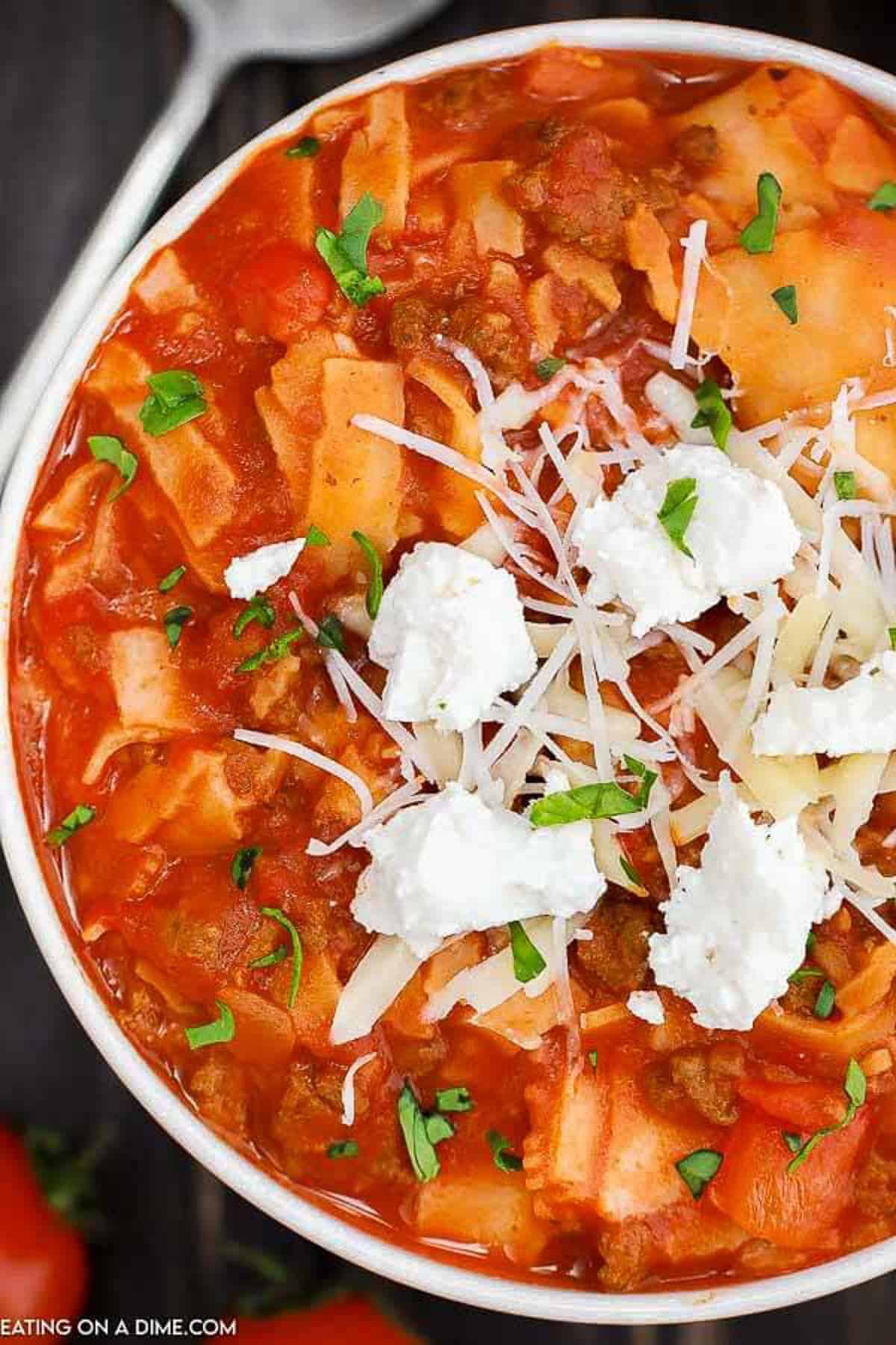 Overview of Lasagna Soup in a Bowl topped with ricotta cheese and shredded parmesan cheese.  