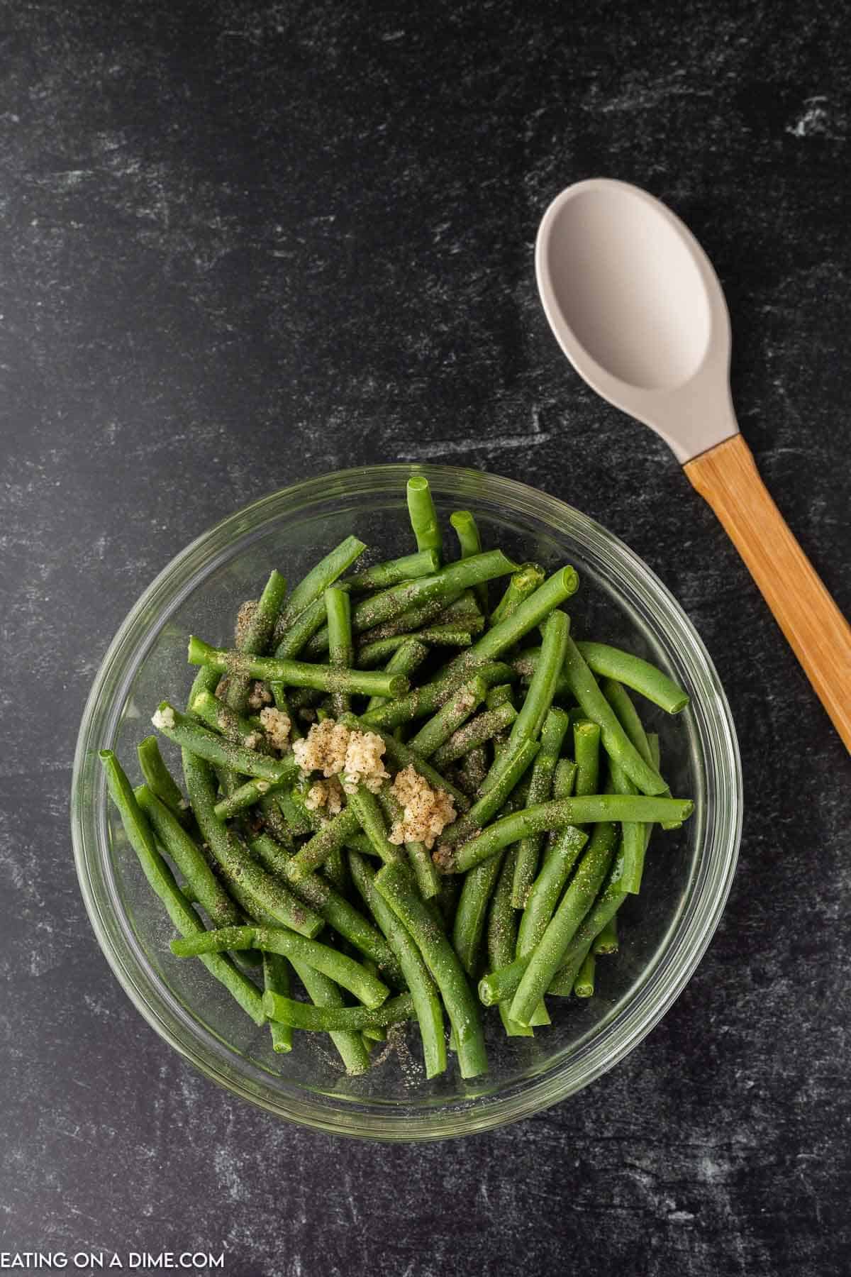 Trimmed green beans in a bowl with olive oil and seasoning