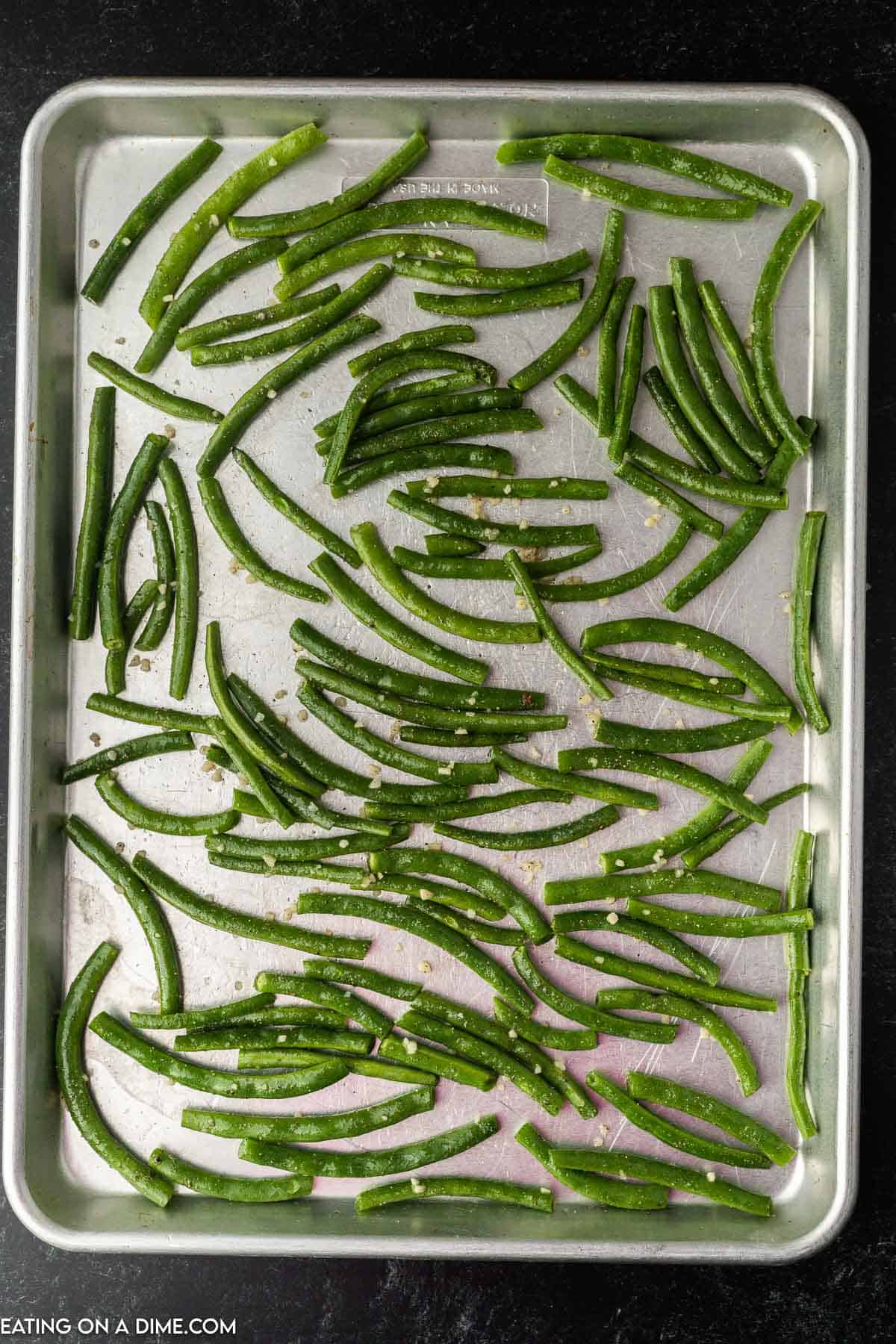 Spreading the green beans on a baking sheet