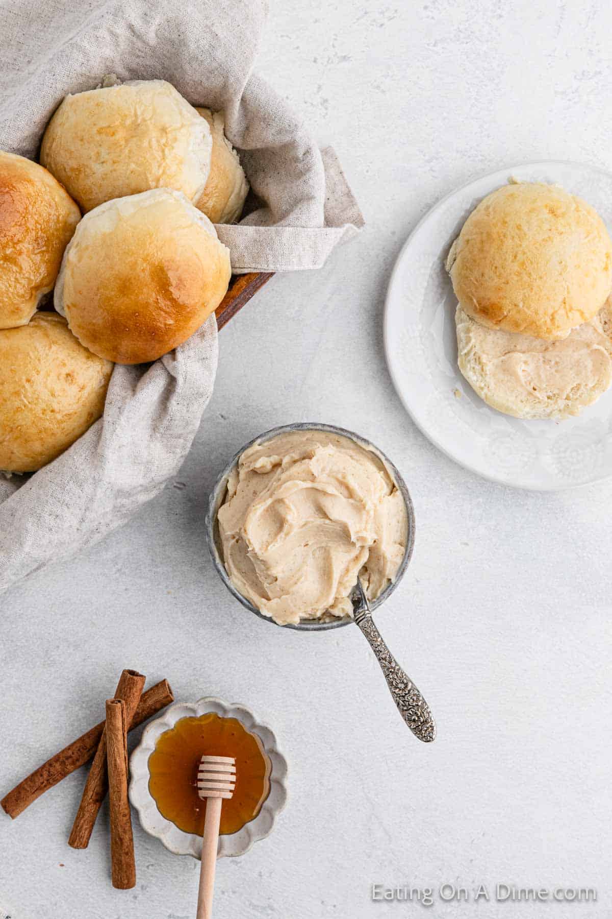 Cinnamon Butter in a bowl with a basket of rolls on the side with a roll topped with spread on the other side