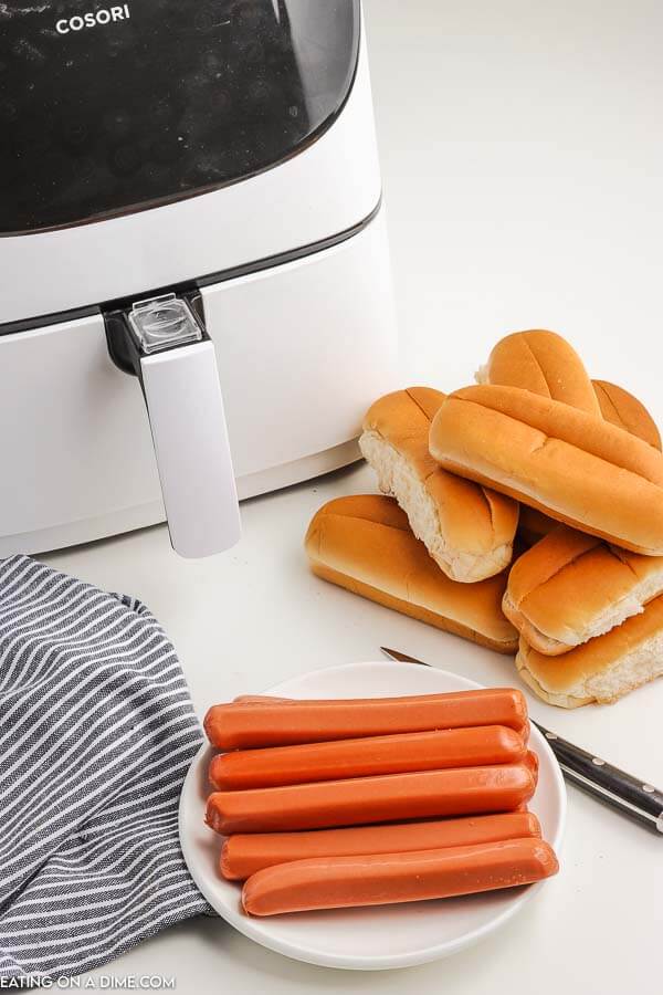 close up image of hotdogs with a knife and buns. 