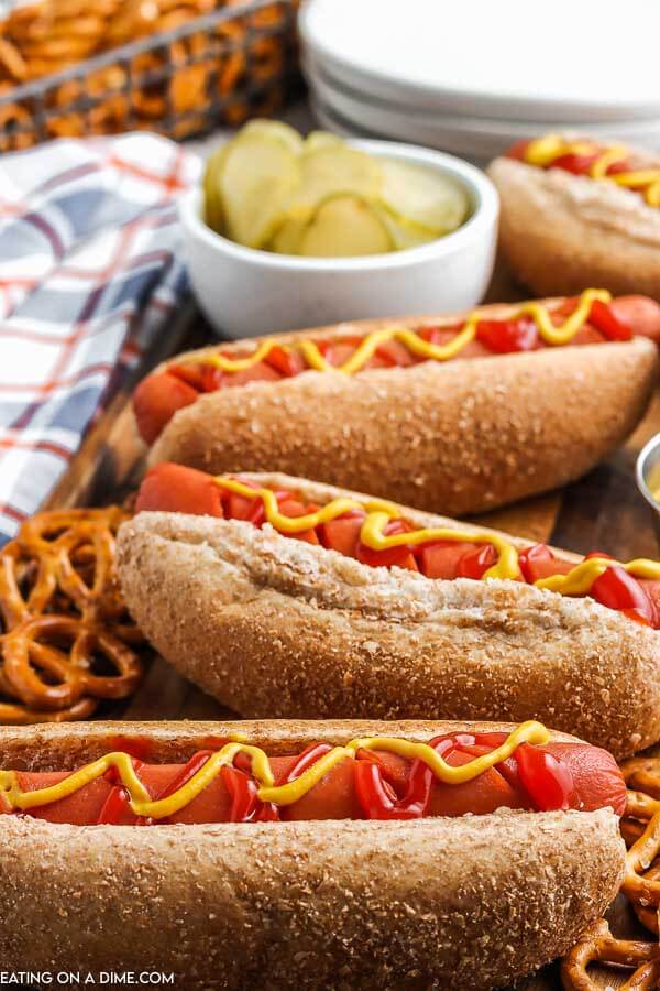 Close up image of hot dogs with a side of pickles, mustard and ketchup