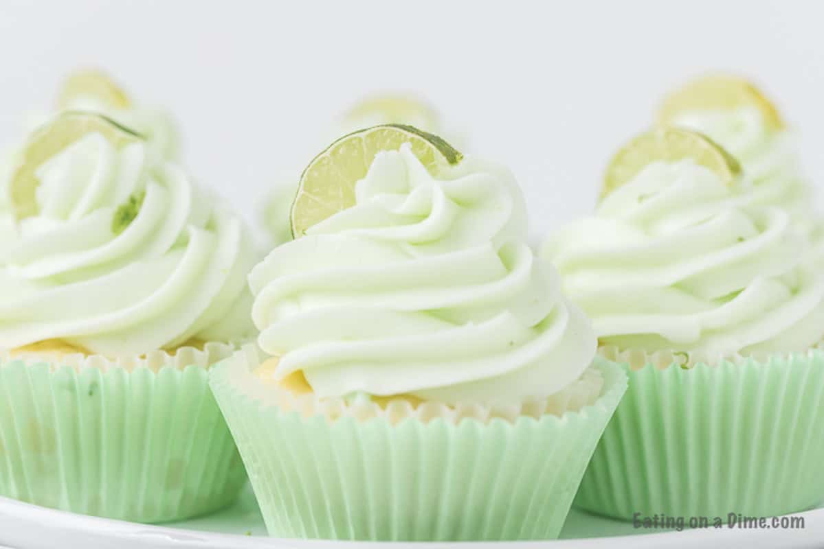 Key Lime Cupcakes on a platter topped with frosting and a lime wedge