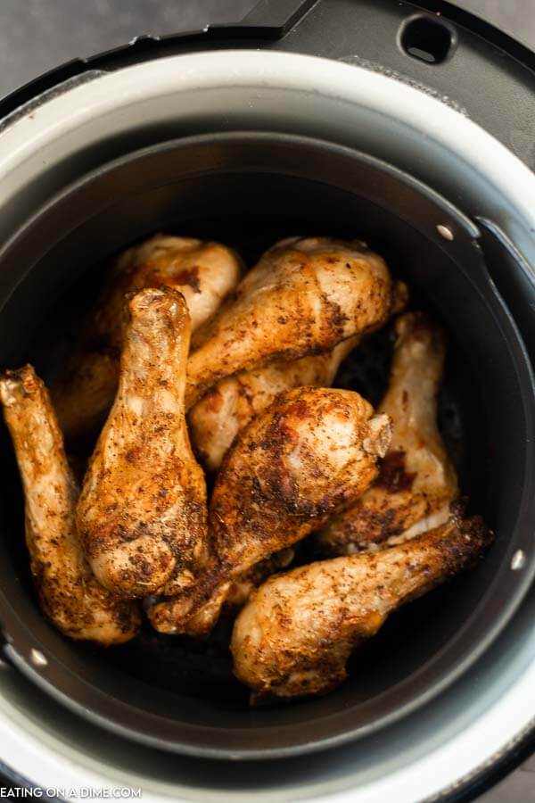 photo of inside of air fryer with cooked chicken legs.