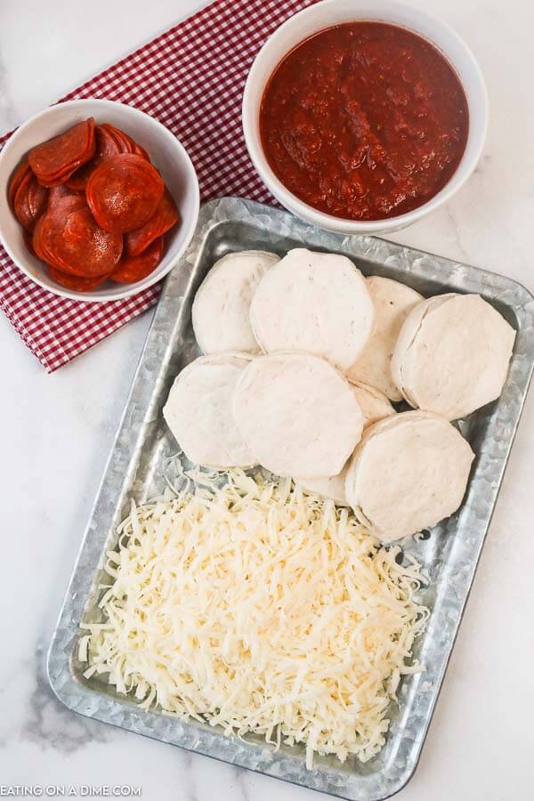 Ingredients needed to make air fryer pizzas: biscuits, shredded cheese, pizza sauce and pepperonis. 
