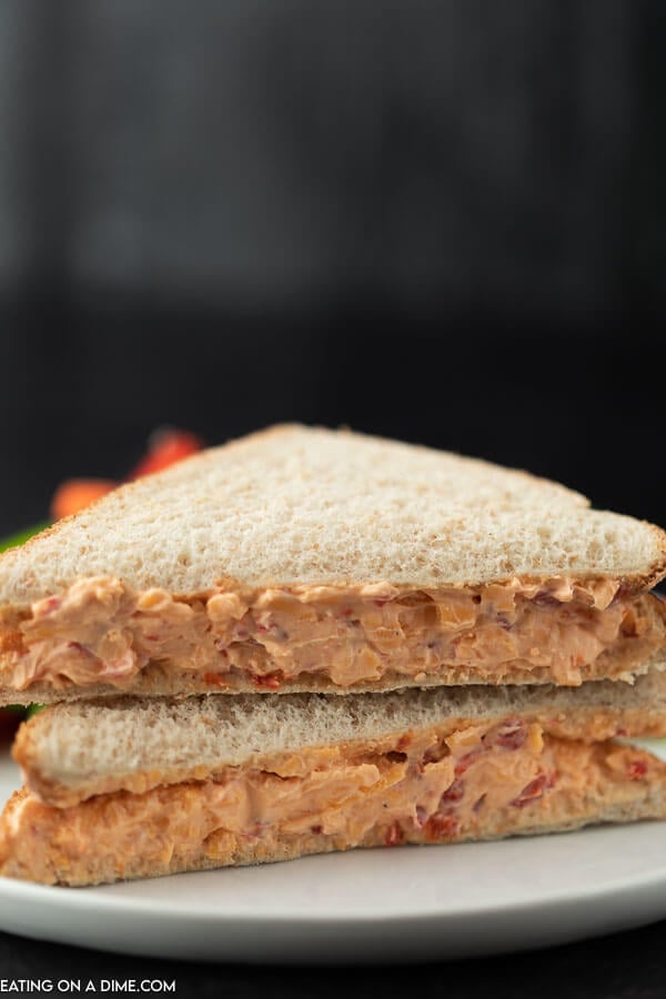 A pimento cheese sandwich cut in half and stacked on top of each other on a white plate 