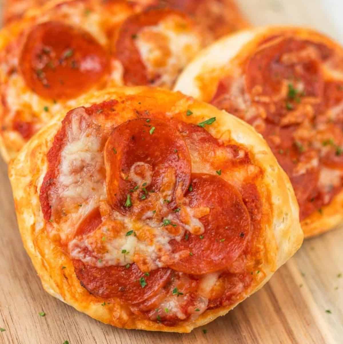 Close up of a small pizza on a wooden platter.