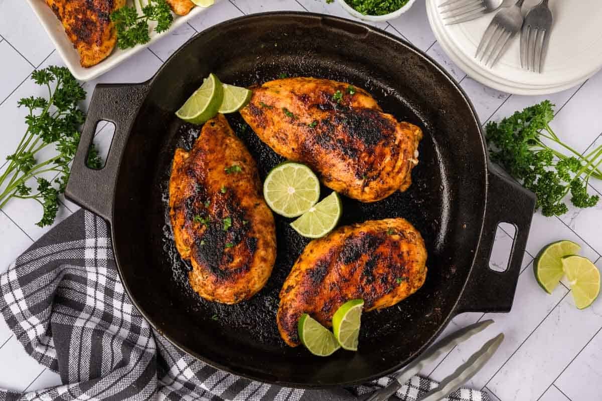 Blackened Chicken in a cast iron skillet with fresh lime wedges