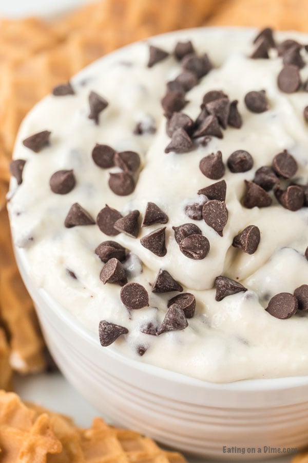 Close up image of Cannoli Dip in a white bowl with chocolate chips on top. 