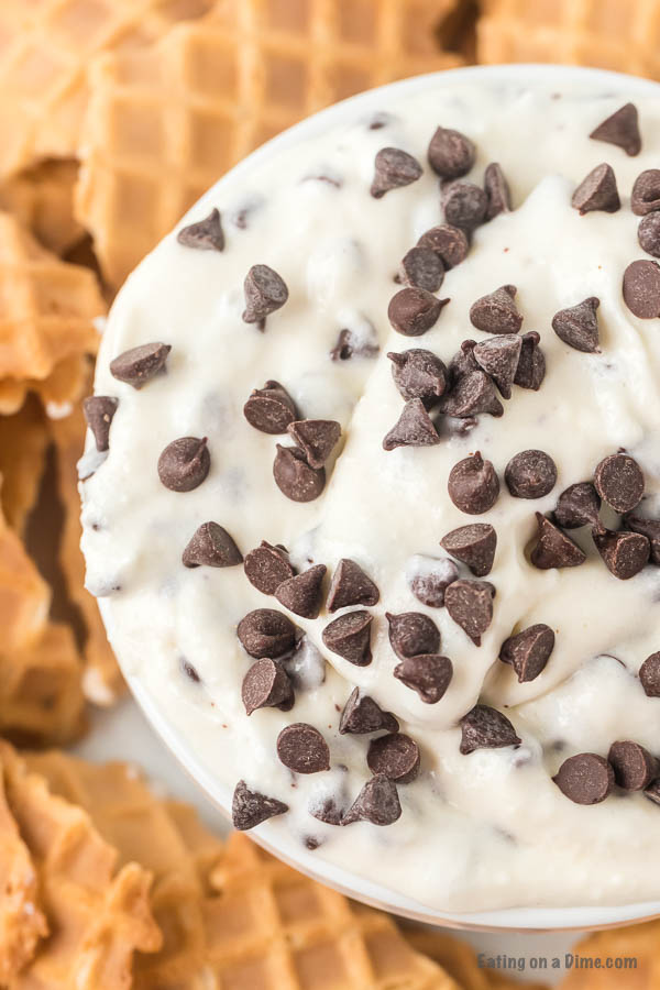 Close up image of Cannoli Dip in a white bowl with broken up cones on the side. 