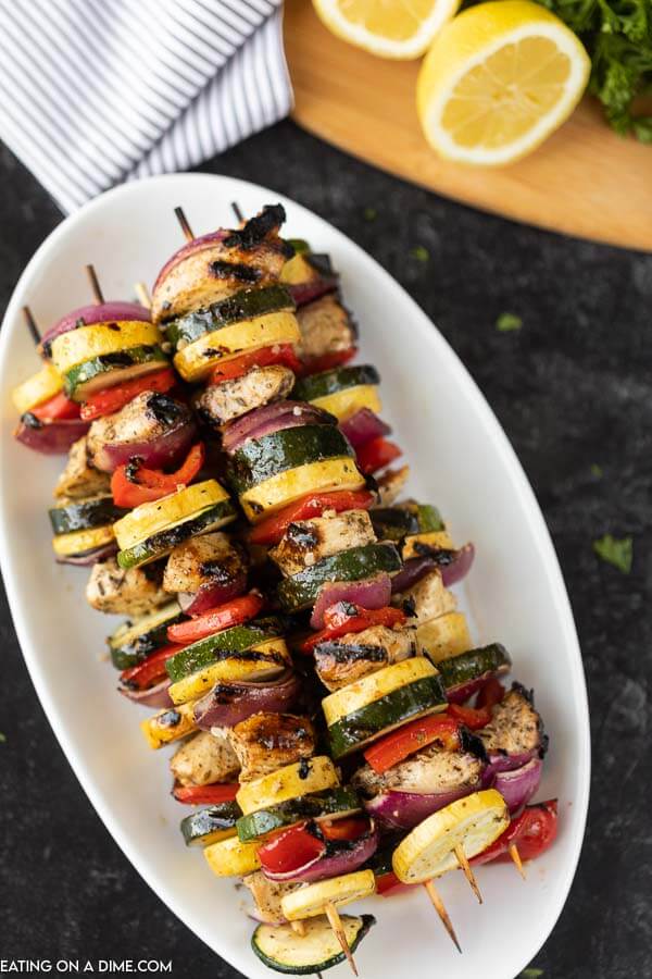 Photo of grilled chicken and vegetable skewers on a white platter.