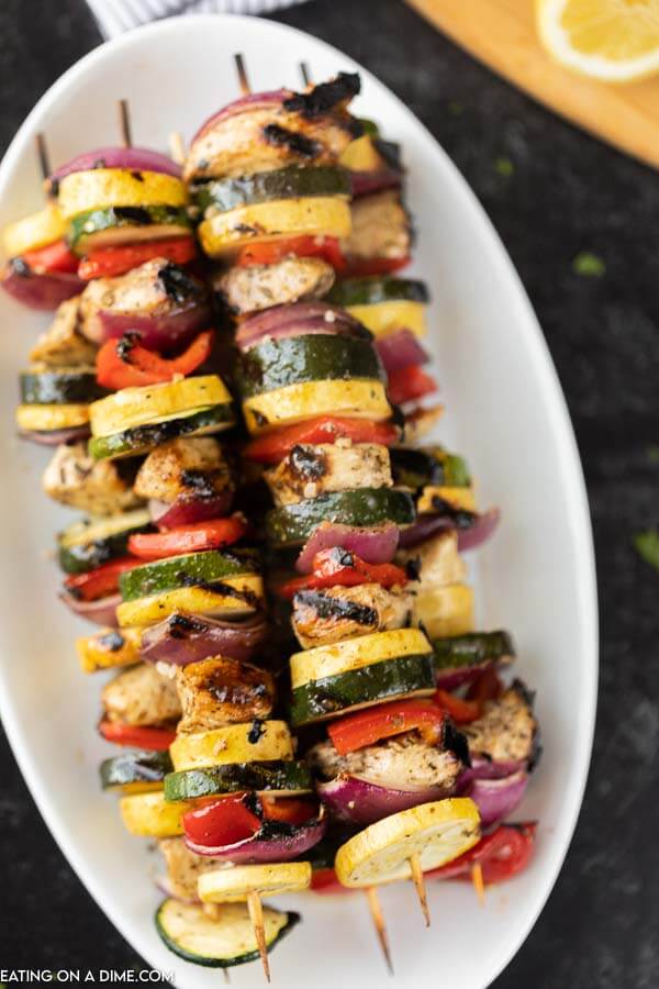 Photo of grilled chicken and vegetable skewers on a white platter.