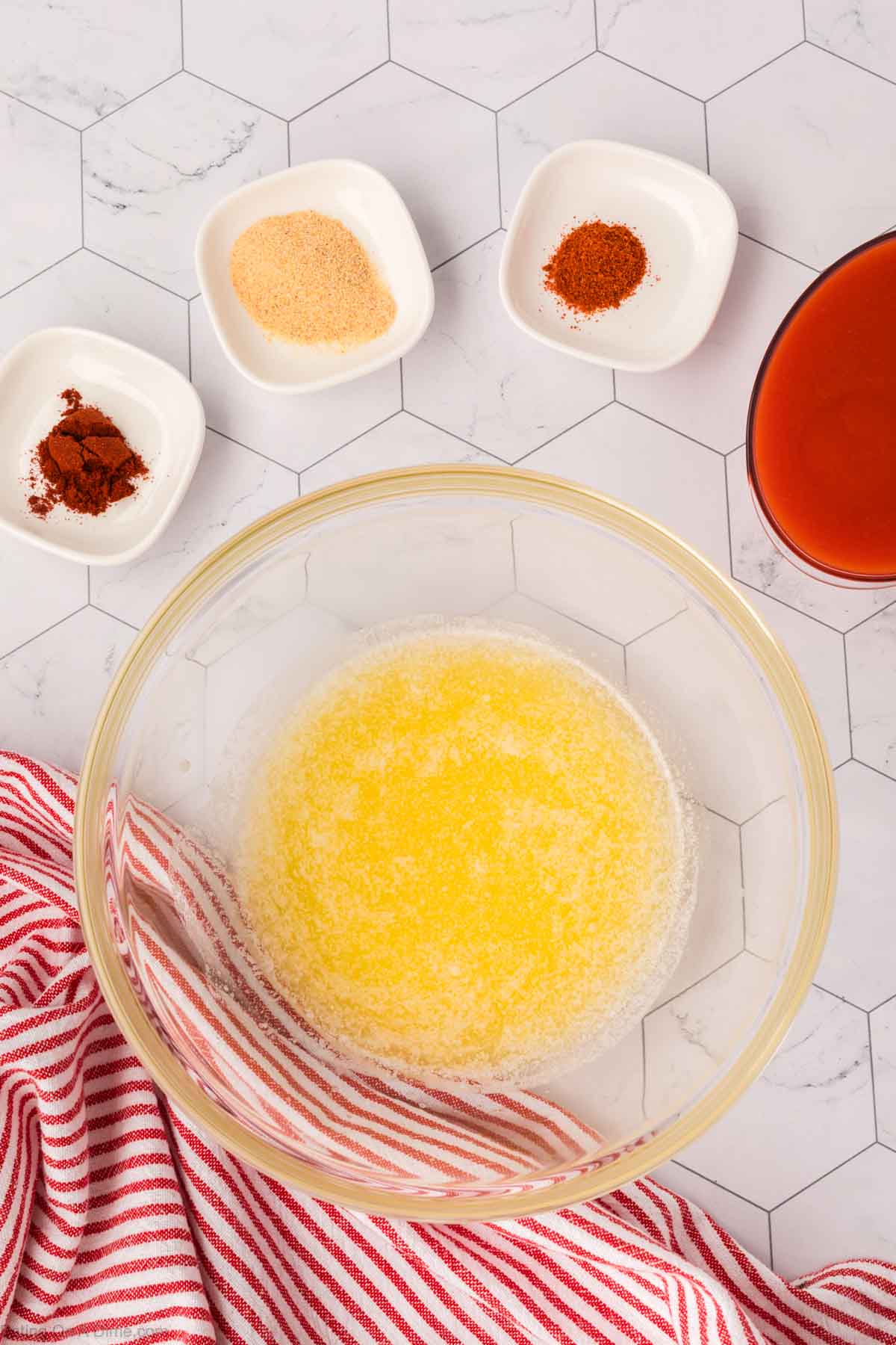 Melted butter in a bowl with small bowls of spices on the side