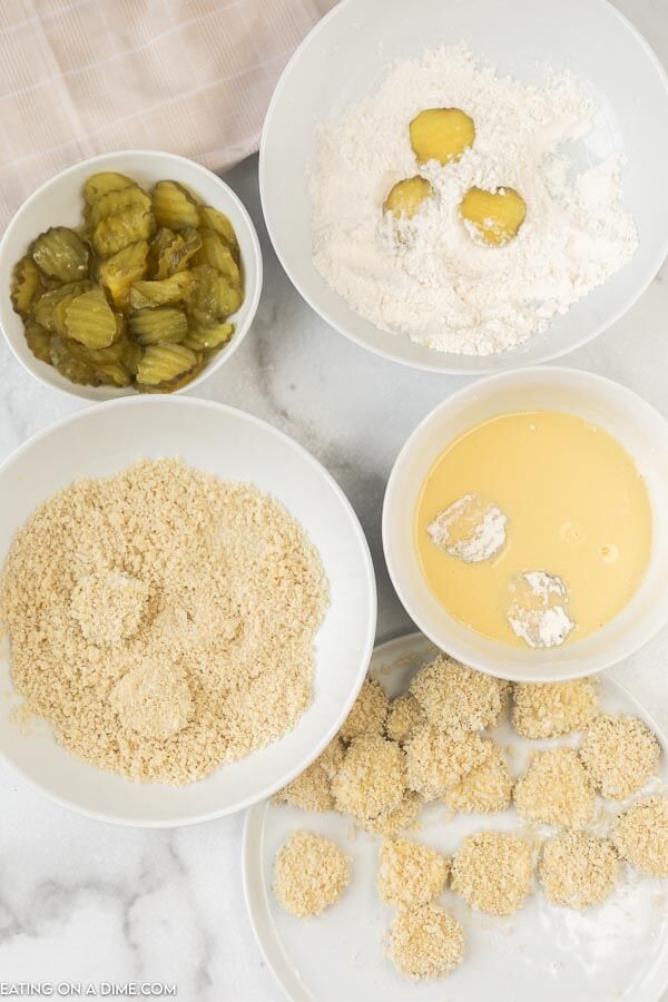 dipping pickles in bowls of egg mixture and breadcrumbs. 