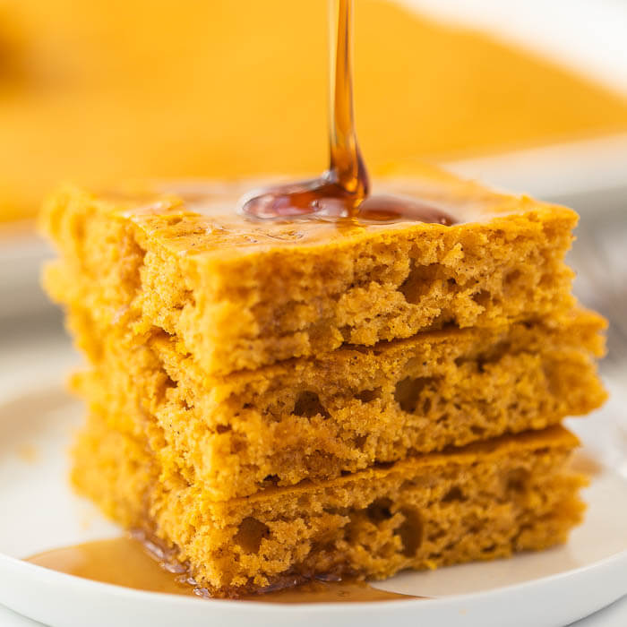 Close up of the syrup being poured on top of the stacked baked pumpkin pancakes. 