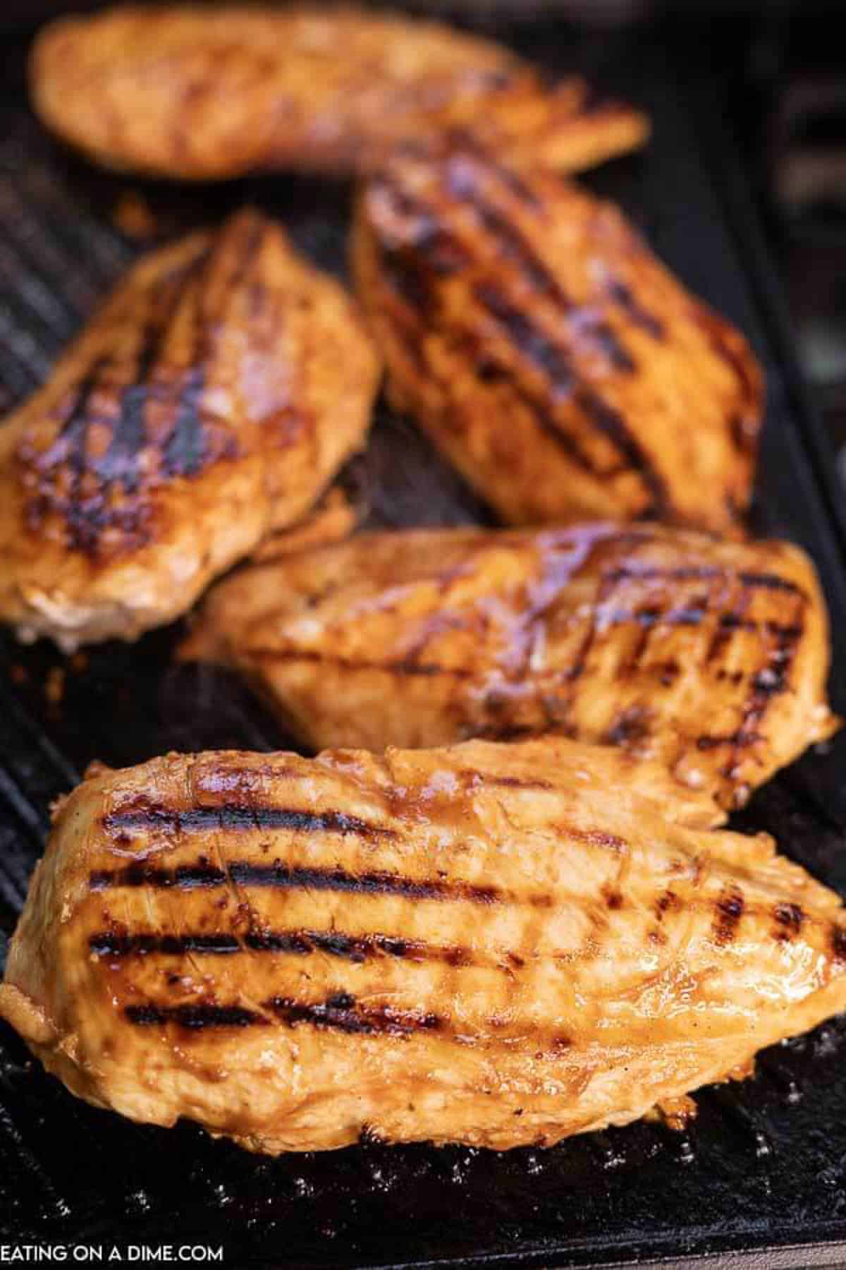 The marinaded chicken breasts cooking on a grill.  