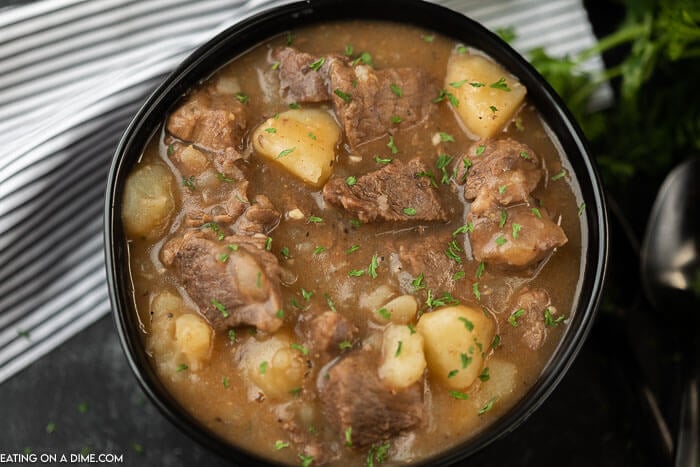 a serving bowl of stew topped with fresh parsley 