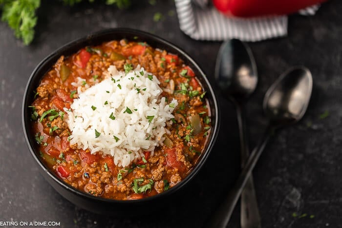 Close up image of stuffed pepper soup in a black bowl with two spoons.