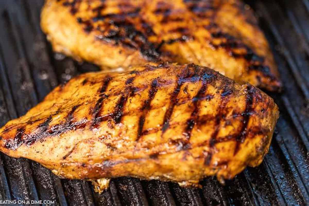 The marinaded chicken breasts cooking on a grill.  