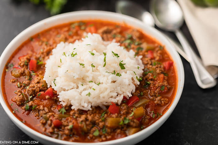 Close up image of stuffed pepper soup with white rice and two silver spoons. 