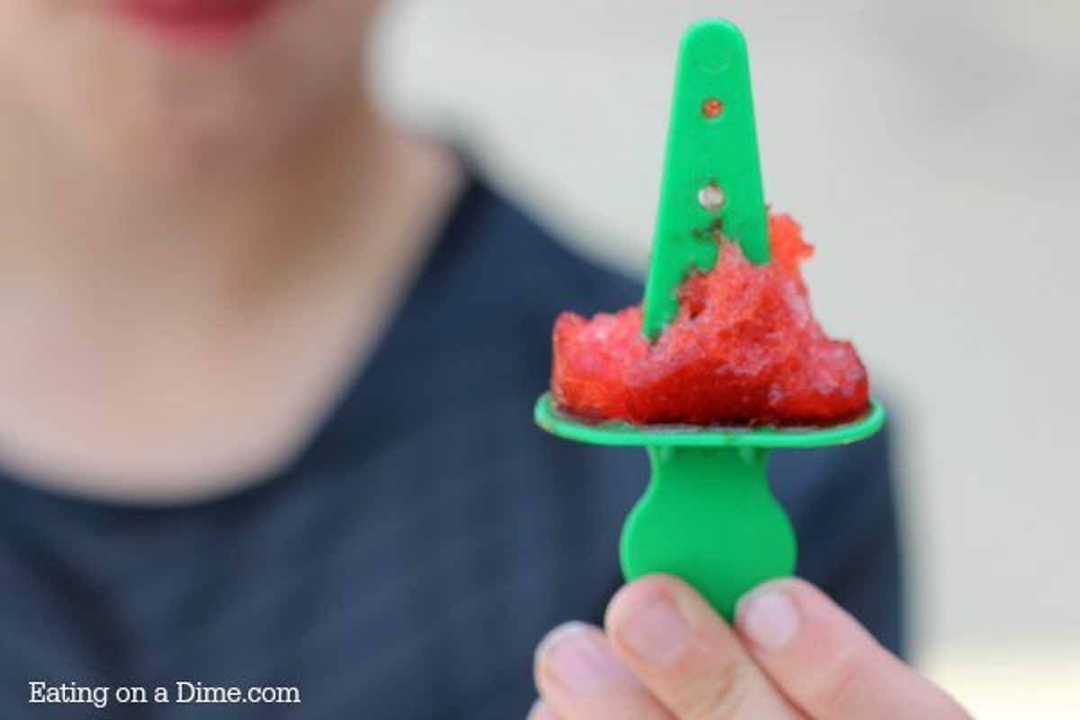 A child holding up an empty popsicle stick and the popsicle has been eaten off the stick. 