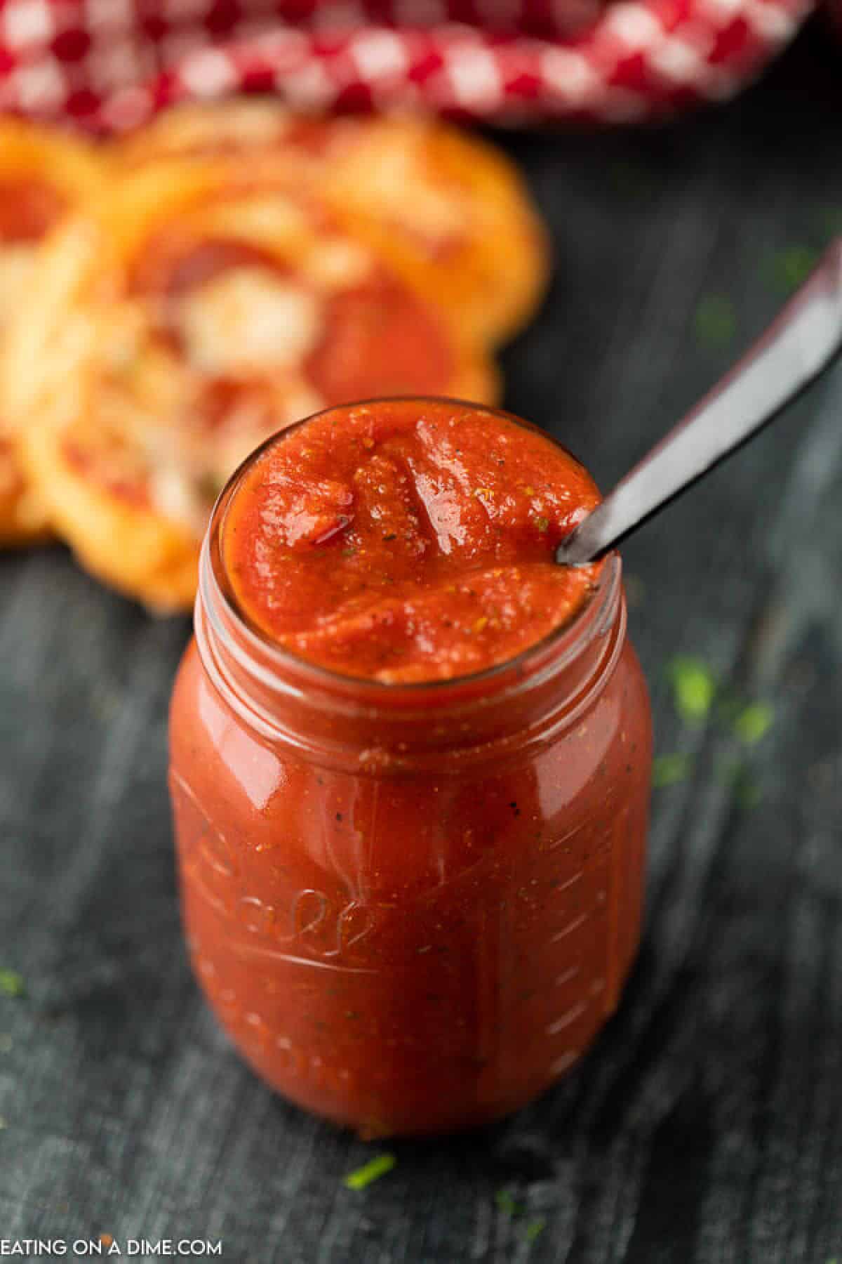 Save money and make homemade pizza sauce. This recipe is so easy and beats anything store bought! Try it with all your favorite dishes. Pizza sauce in a mason jar with a silver spoon in it.