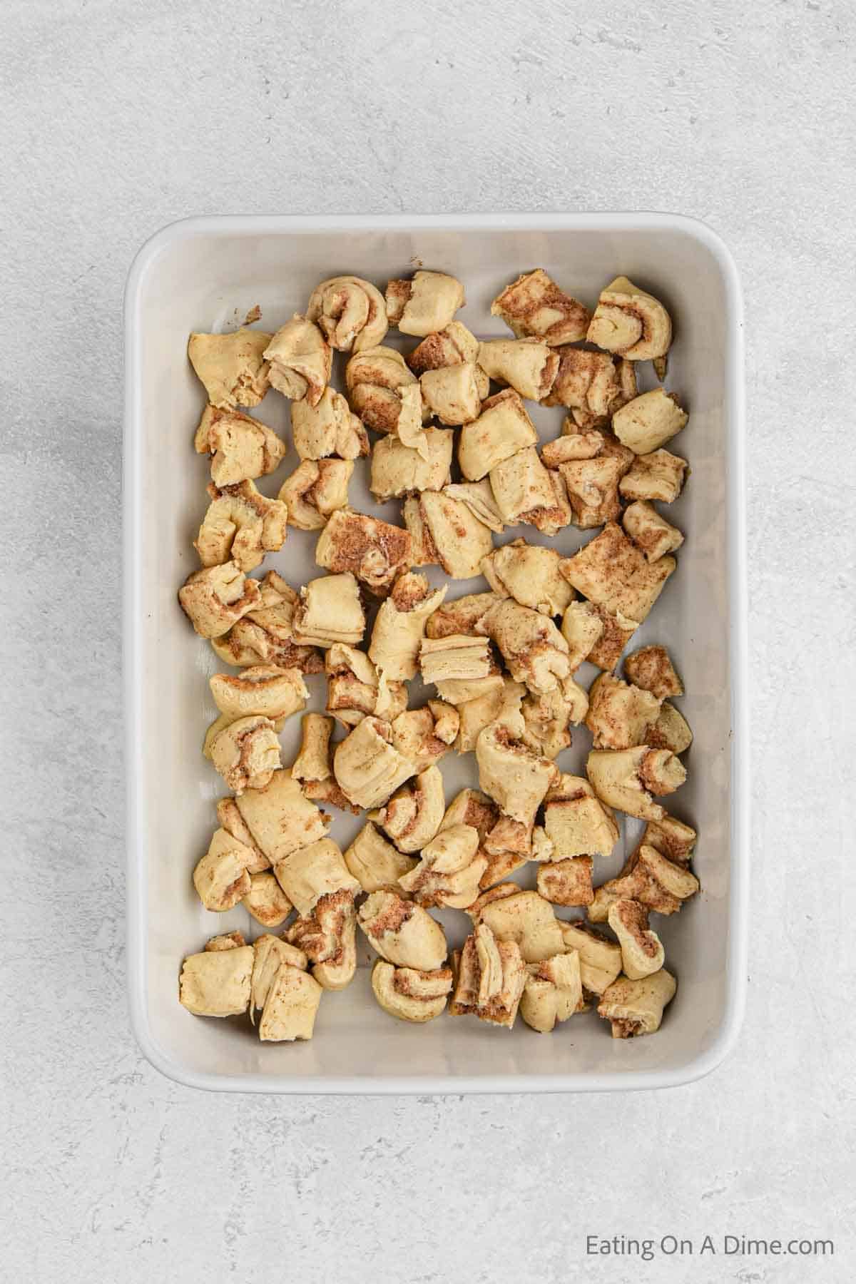 Placing the cinnamon roll pieces in a casserole dish