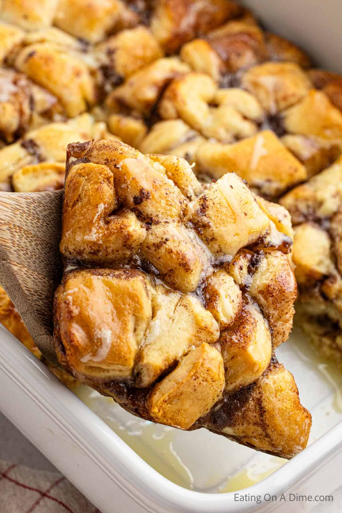 Close up image of a serving of cinnamon roll french toast casserole on a wooden spatula