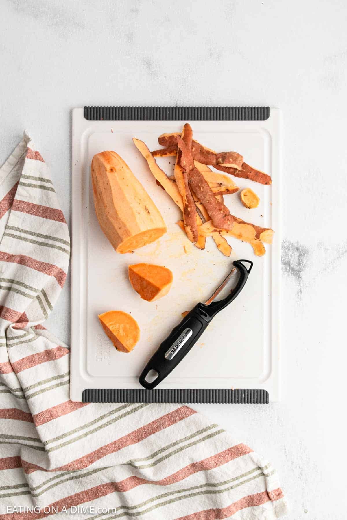 Peeling sweet potatoes on a cutting board.