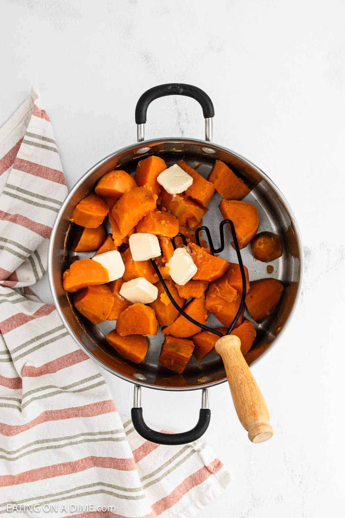 Cooked sweet potatoes in a large pot topped with butter.