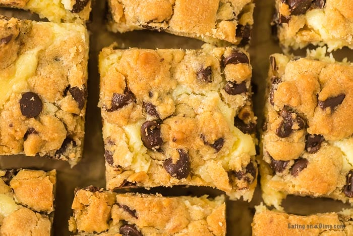 Close up image of chocolate chip cookie cheesecake bars cut in squares. 
