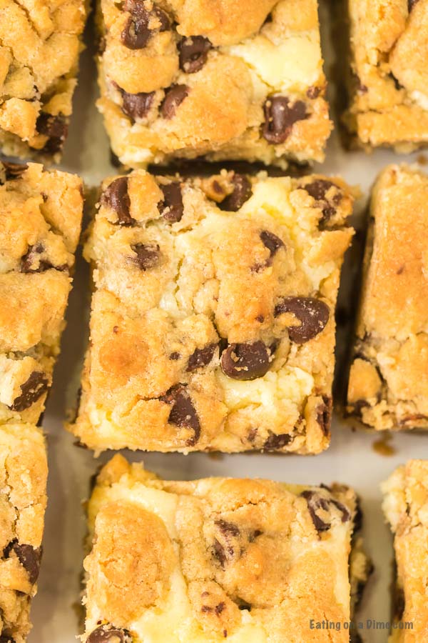 Close up image of chocolate chip cookie cheesecake bars cut in squares. 