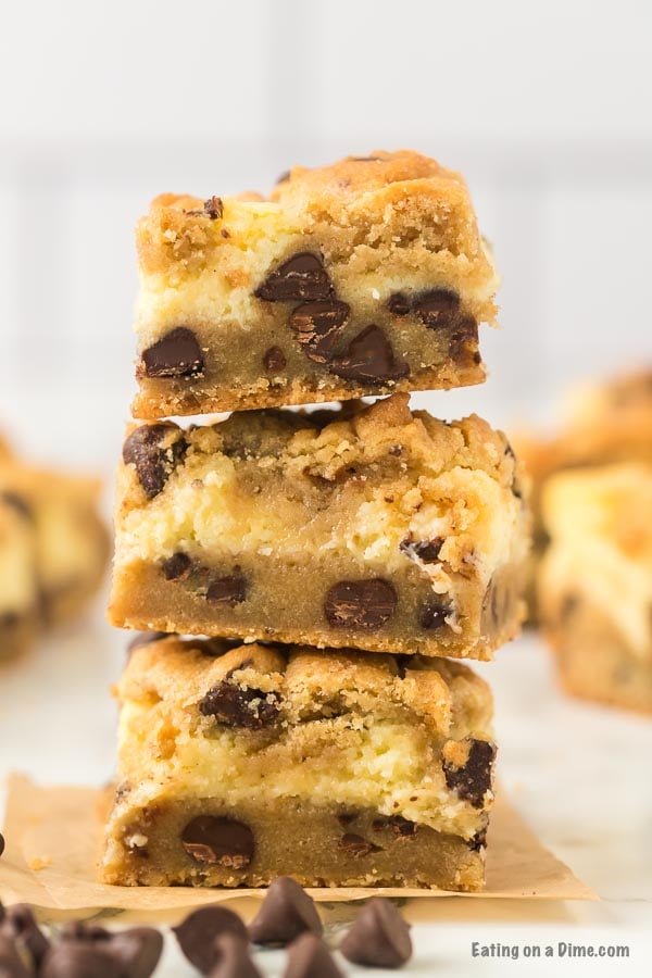 Close up image of chocolate chip cookie cheesecake bars stack on top of each other. 