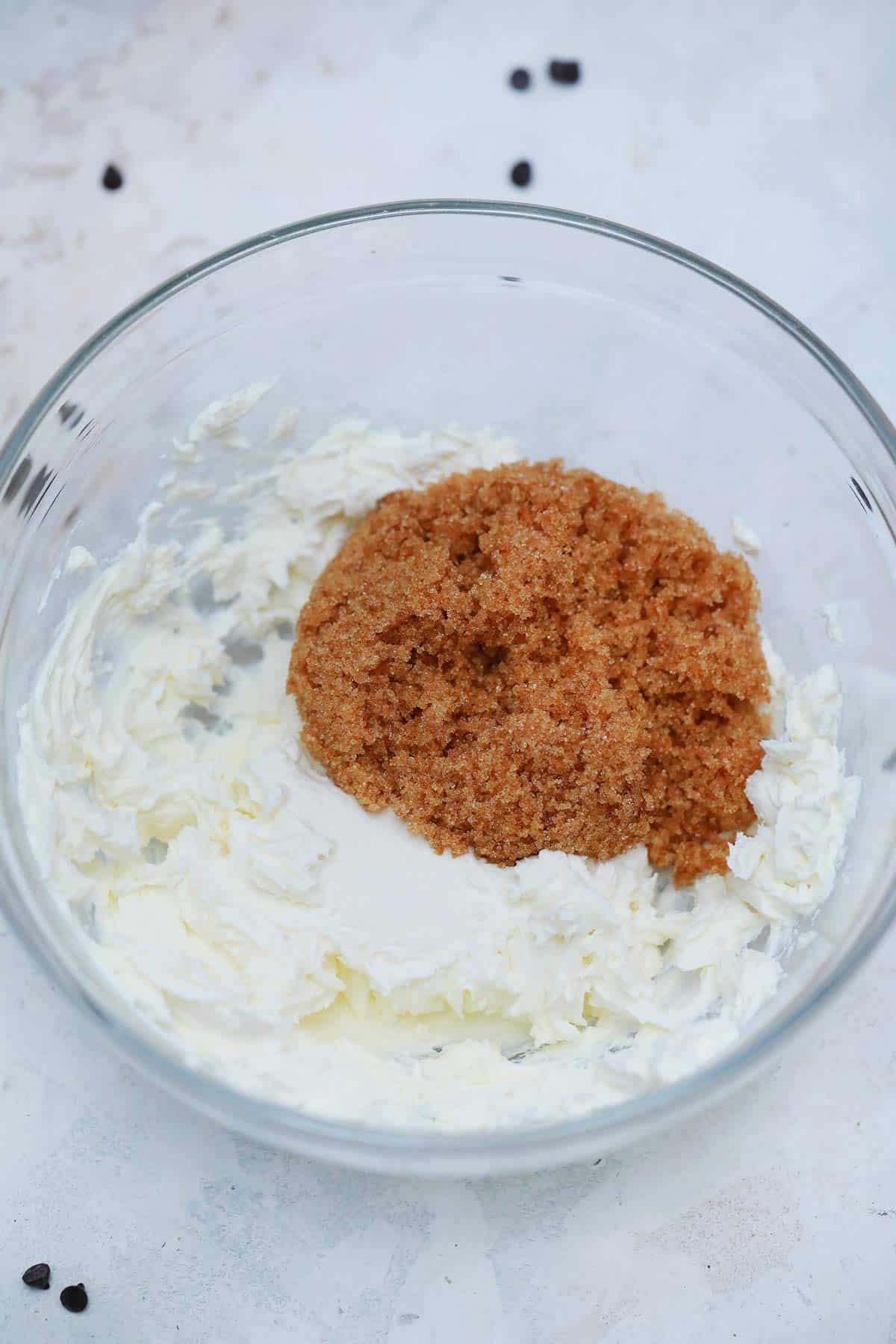 Blended cream cheese in a bowl topped with brown sugar.