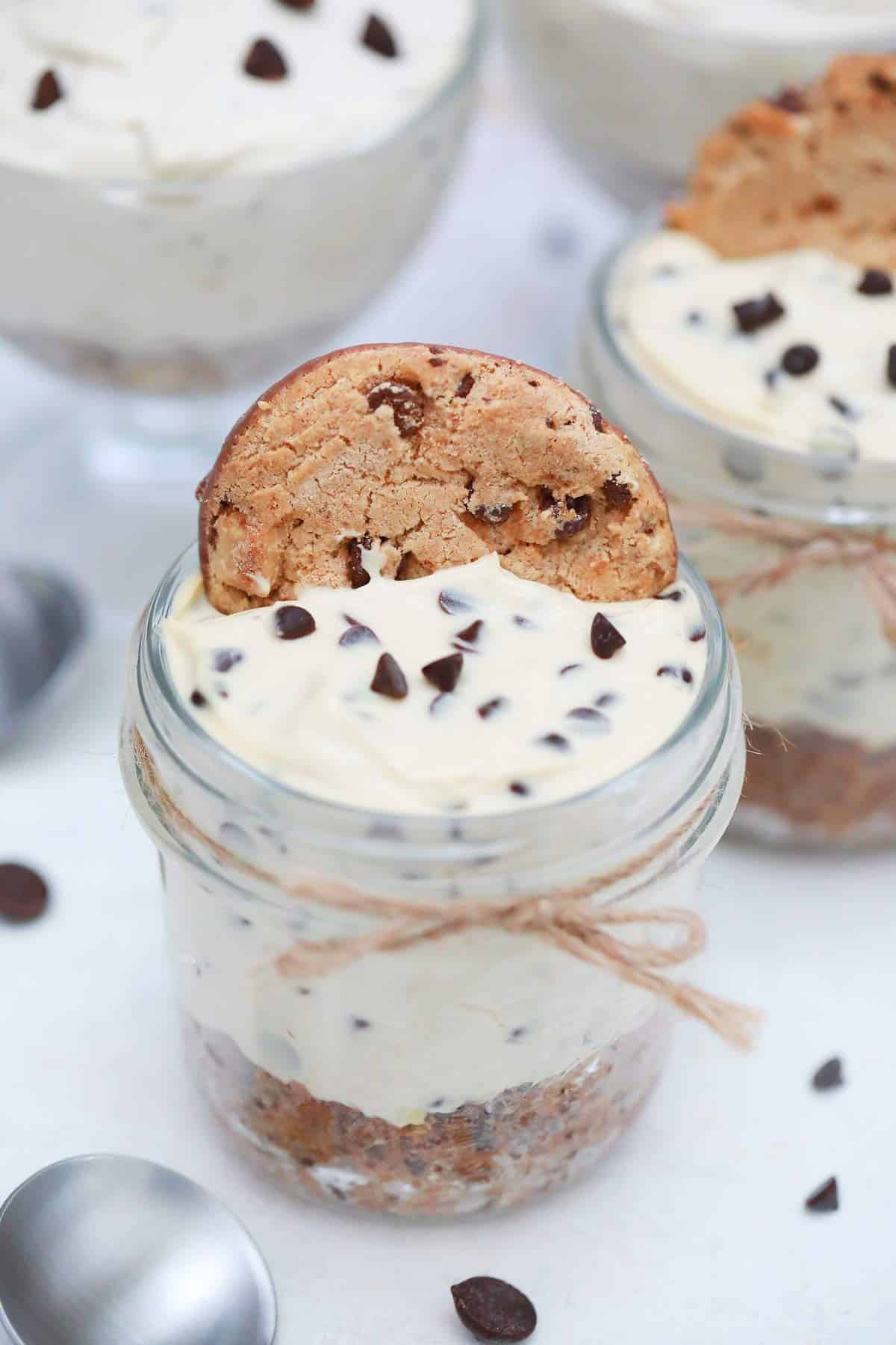 Mini jars of chocolate chip cheesecake topped with chocolate chip cookie.