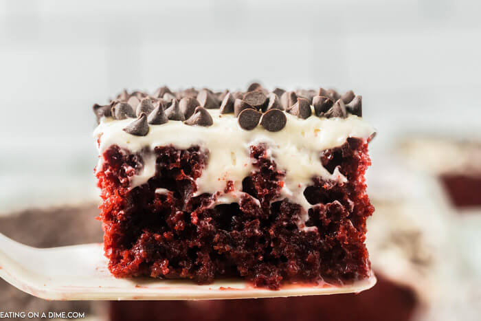 Up close photo of slice of Red Velvet Poke Cake on a spatula. 