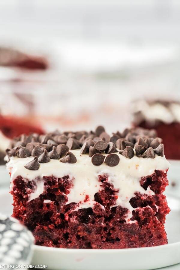 Up close photo of slice of Red Velvet Poke Cake topped with chocolate chips. 