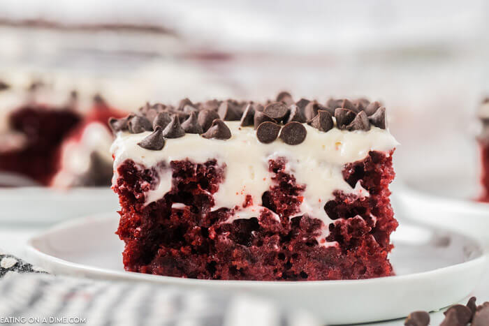 Up close photo of slice of Red Velvet Poke Cake topped with chocolate chips. 