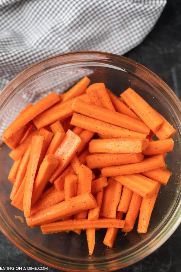 Mixing the carrots with the seasoning and oil in the bowl