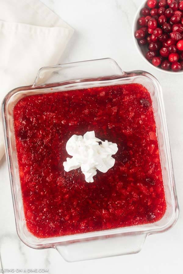 baking dish with cranberry salad and whipped cream on top