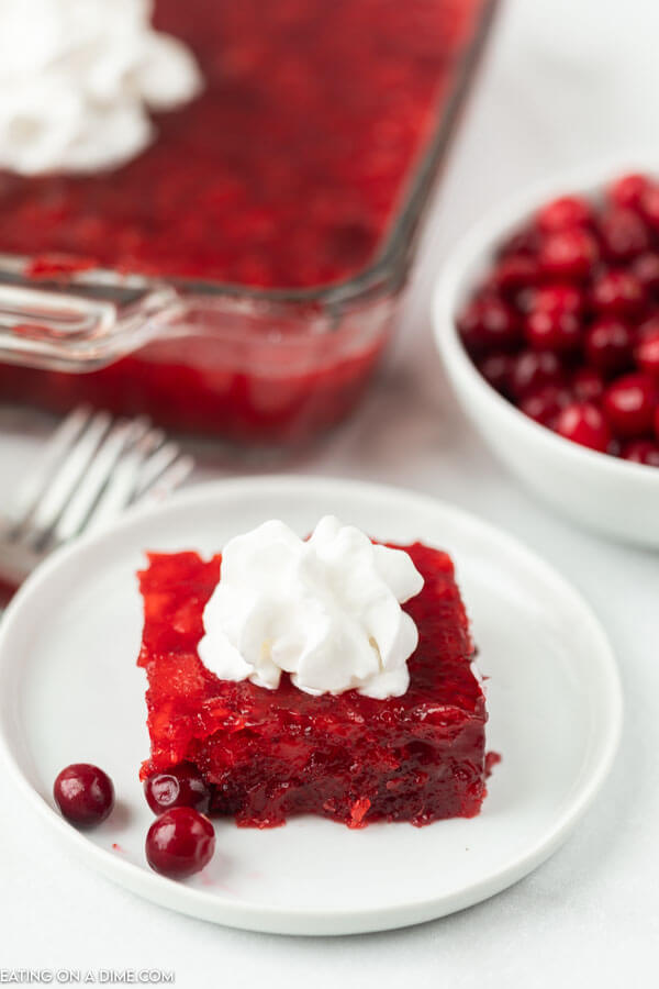 serving of cranberry salad on a plate topped with whipped cream.