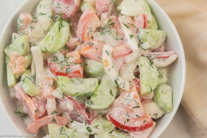 closeup photo of creamy cucumber and tomato salad in a white bowl.